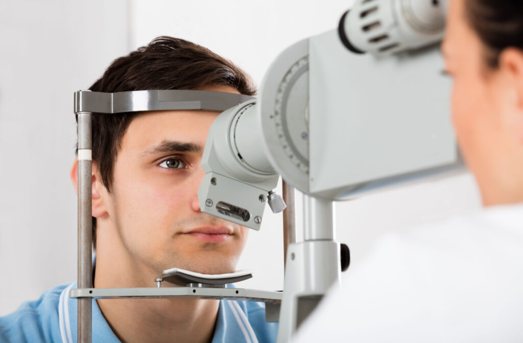 A man sitting in an optometrist's office and looking into a machine that tests his vision.