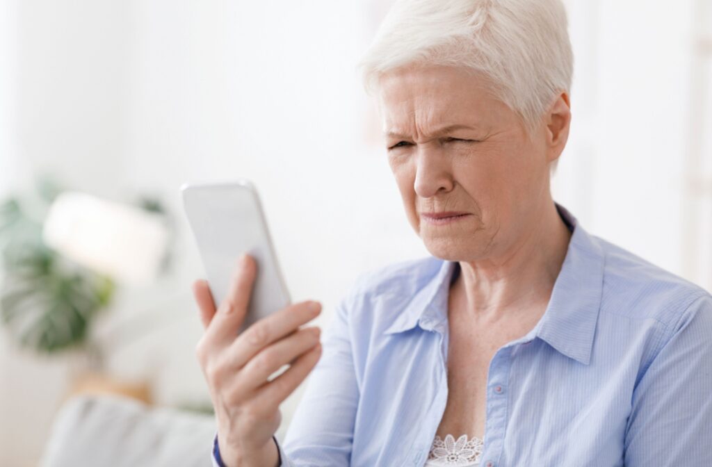 An older adult woman squinting at her phone