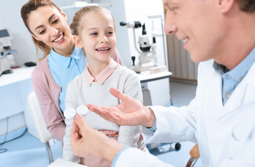 An optometrist discussing contact lens care, wear, and use with a young child and their mother.