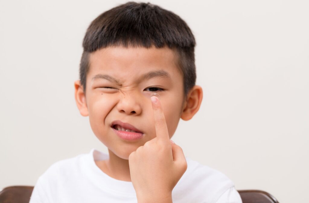 A young child attempts to put in his contact lenses.