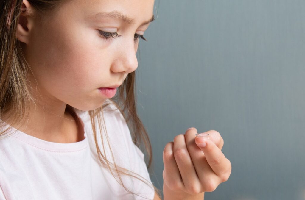 A child stares curiously a MiSight contact lense gently placed on her finger